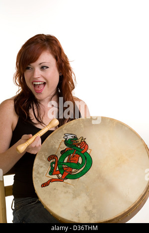 Junge und moderne rote Leitung Mädchen spielen Bodhran Trommel Stockfoto