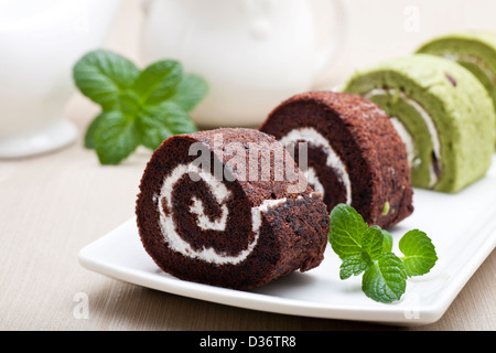 Schokoladen-Biskuitrolle mit grüner Minze Blätter Stockfoto