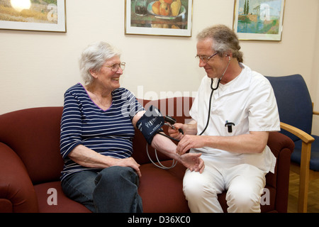 Essen, Deutschland, eine geriatrische Krankenschwester misst Blutdruck eines Patienten Stockfoto