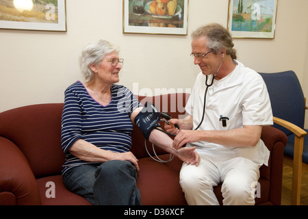 Essen, Deutschland, eine geriatrische Krankenschwester misst Blutdruck eines Patienten Stockfoto