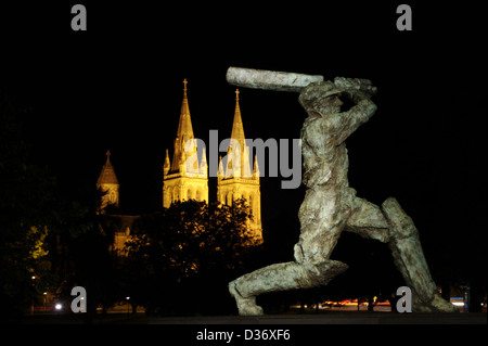 Sir Donald Bradman-Statue in Adelaide, South Australia in der Nacht mit St. Peters Dom im Hintergrund Stockfoto