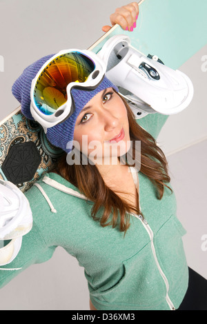 Snowboard und Spaß liebende lächelnd weiblich in Petrol mit ihrer Ausrüstung Stockfoto