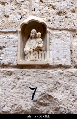 Clay Wandnische mit Cast Figuren von der Jungfrau Maria und Jesuskind und unter der Nummer 7. Die Nische ist auf einer Steinmauer Stockfoto