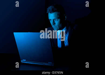 Ein Mann arbeitet auf einem Laptopcomputer in der Dunkelheit Stockfoto