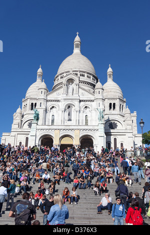 Eine große Schar von Menschen stehen, gehen oder sitzen auf den Stufen vor der Basilika Sacre Coeur auf dem Montmartre, Paris. Stockfoto