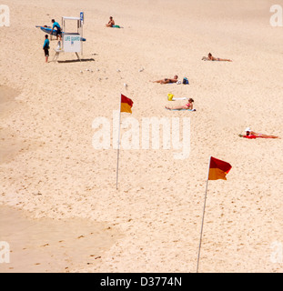 Sonnenanbeter am Bondi Beach, Sydney, Australien neben dem Bademeister Turm mit Warnung Flags Stockfoto