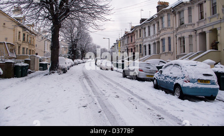 Autos parken in terrassenförmig angelegten Straße im Schnee, Brighton, UK Stockfoto