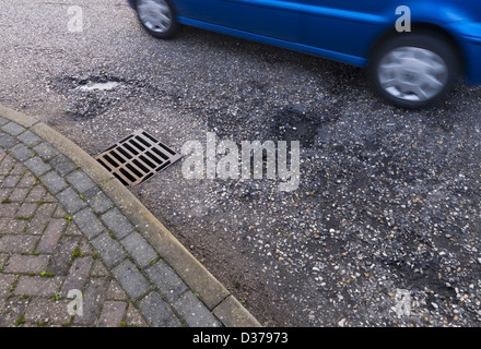 Auto fahren über Schlaglöcher und einer bröckelnden Straßendecke. Stockfoto