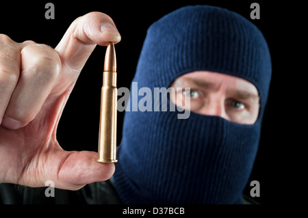 Ein Terrorist mit einer Ski-Maske als Tarnung hält eine große automatische Gewehrkugel. Stockfoto