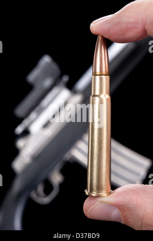 Ein Mann hält eine Hochleistungs-Kugel vor einer automatischen Maschinengewehr. Stockfoto