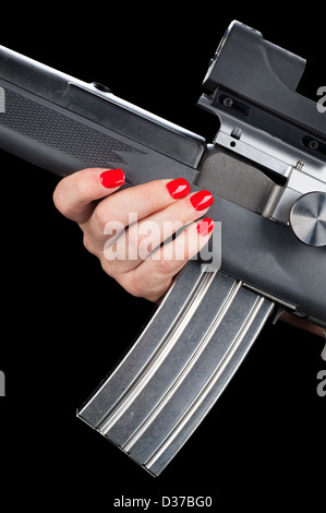 Eine Frau mit ziemlich rot lackierten Fingernägeln hält auf einem Sturmgewehr mit einem voll beladenen Magazin. Stockfoto