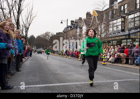 Menge Uhren jungen Konkurrenten (Kinder), Laufen & spiegeln Pfannkuchen, die in traditionellen, Pancake Race - The Grove, Ilkley, West Yorkshire, UK. Stockfoto