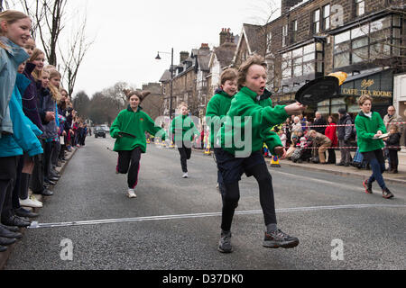 Menge Uhren jungen Konkurrenten (Kinder), Laufen & spiegeln Pfannkuchen, die in traditionellen, Pancake Race - The Grove, Ilkley, West Yorkshire, UK. Stockfoto