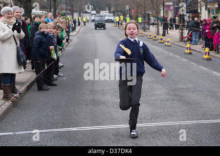 Menge Uhren Mädchen konkurrieren, nehmen teil, Laufen & spiegeln Pfannkuchen in traditionellen Ilkley Rotary Pancake Race - The Grove, Ilkley, West Yorkshire, UK. Stockfoto