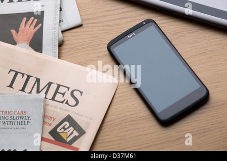 HTC One X + Android-Smartphone mit einem leeren Bildschirm neben eine Auswahl von Broadsheet Qualitätszeitungen. Stockfoto