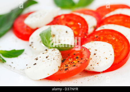 Tomate und Mozzarella mit Basilikum Blätter auf einem Teller Stockfoto