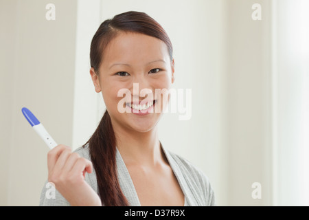 Frau unter Schwangerschaftstest im Badezimmer Stockfoto