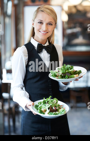 Dänemark, Aarhus, Porträt der jungen Kellnerin hält Teller mit Salat Stockfoto