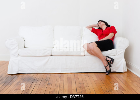 Geschäftsfrau, die entspannend auf sofa Stockfoto