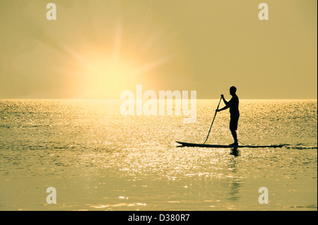 USA, North Carolina, Nags Head, Mann stehend auf Paddel Board bei Sonnenuntergang Stockfoto