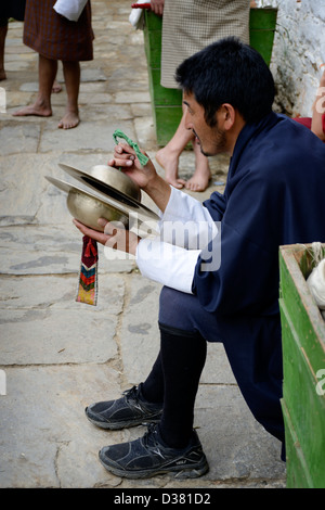 Bhutan Mann in traditionellen Gho spielt Symbole in eine Tanz- und Generalprobe für ein Festival, Jakar Dzong, 36MPX, HI-RES Stockfoto