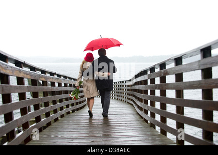 Paare, die auf Holzmole in Regen Stockfoto