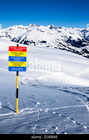 Ski-Spuren führt darüber hinaus eine ignorierte Warnung zu unterzeichnen, in mehreren Sprachen, Obersaxen, Graubünden, Schweiz Stockfoto