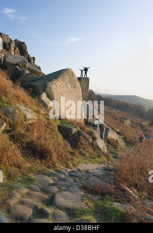 Zwei jungen stehen siegreich auf einem riesigen Felsbrocken auf Stanage Edge, Peak District, Derbyshire, UK Stockfoto