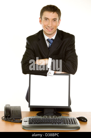 Junger Geschäftsmann stützte sich auf einen Computer Bildschirm stehen auf einem Tisch in der Nähe des Telefons auf weißem Hintergrund Stockfoto