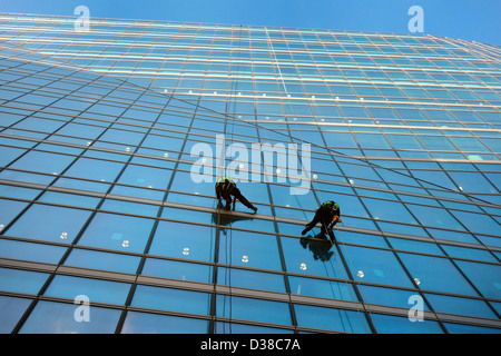 Zwei Männer Abseilen beim Fensterputzen von einem großen Glas-Bürogebäude Stockfoto