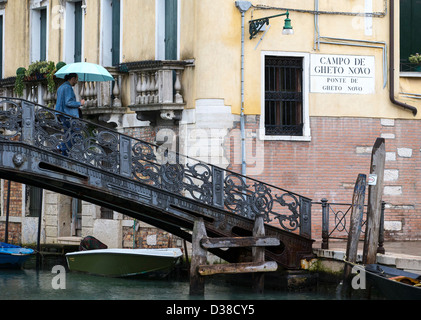 Ein Mann mit einem grünen Dach eine eiserne Brücke in das Ghetto in Venedig (Ponte de Gheto Novo) absteigend Stockfoto