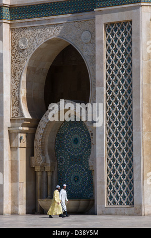 Marokkanische Männer tragen Jalabiyas vorbei an eines der Tore der Hassan II Moschee in Casablanca, Marokko Stockfoto