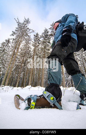 Nahaufnahme von Wanderer tragen Schneeschuhe auf Füßen beim Schneeschuhwandern im Wald im Tiefschnee im winter Stockfoto