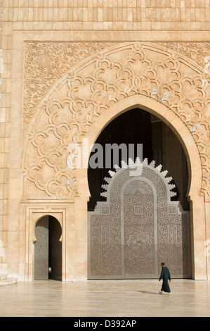 Mann trägt einen Fez, vorbei an einer der Türen der Hassan II Moschee in Casablanca, Marokko Stockfoto