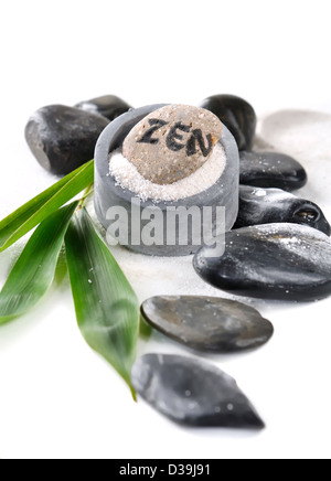 Zen Kieselstein in Sand mit Balck Kies und Bambus Blätter auf weißem Hintergrund Stockfoto