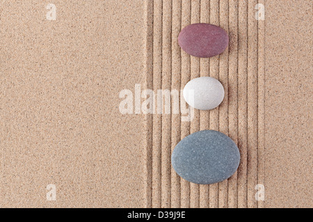 Drei farbige Kieselsteine auf einen geharkt Sand Zen-Garten. Stockfoto