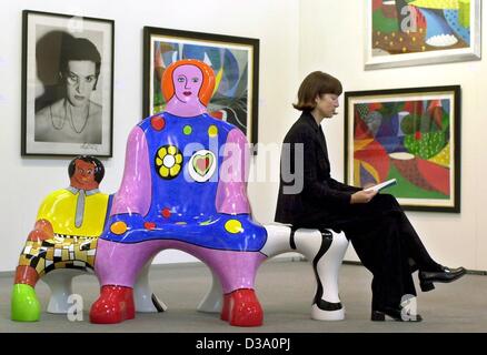 (Dpa) - sitzt eine Frau auf einer "Mutter & Kind" Bank von Niki de Saint Phalle an der 13. Kunstmesse in Frankfurt am Main, 27. April 2001 entworfen. Der französische Maler und Bildhauer Niki de Saint Phalle starb im Alter von 71 in San Diego, USA, 21. Mai 2002. Nach ihrer Familie erlitt sie einen langen und schweren illnes Stockfoto