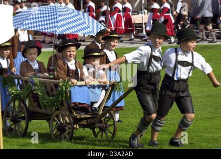 (Dpa) - zwei jungen in traditionellen Trachten einen Heuwagen mit jüngeren Mädchen und Jungen auf eine Kostüm-Festival in Altötting, Oberbayern, 21. Juli 2002 ziehen. Das Festival lockte 8.000 Menschen aus 125 Kostüm Verbände und startete mit einem Open-Air-Gottesdienst. Stockfoto