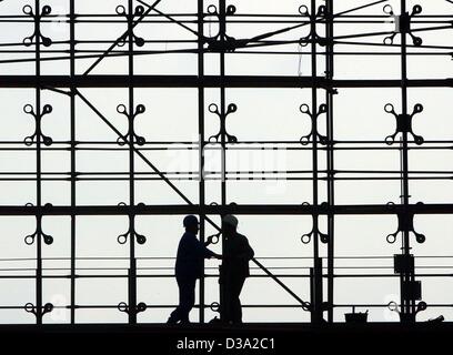 (Dpa) - die Silhouetten von zwei Bauarbeiter sind an der Fassade in der Lehrter Bahnhof in Berlin, 29. Mai 2002 gesehen. Stockfoto