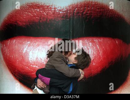 (Dpa-Dateien) - ein Datei-Bild datiert Oktober 1994 zeigt ein paar küssen und umarmen einander vor riesigen Bild von roten Lippen am Bahnhof in Frankfurt am Main station. Stockfoto