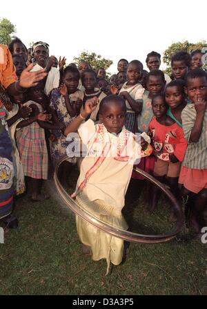 Ein kleines Mädchen wird von anderen Kindern jubelten, als sie Hula-hoop mit einem alten Zyklus Reifen im Dorf Kalambo, nördlichen Malawi, 13. Juni 2001 spielt. Stockfoto