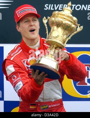 (Dpa) - deutsche Ferrari-Pilot Michael Schumacher hält seine Trophäe nach dem Gewinn der britischen Formel Eins Grand Prix in Silverstone, 7. Juli 2002. Stockfoto