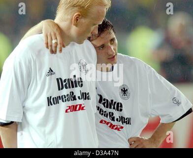 (Dpa) - deutsche vorwärts Oliver Neuville (R) umarmt enttäuscht sein Team Mate Mittelfeldspieler Carsten Ramelow nach der Siegerehrung von der 2002 FIFA World Cup Korea/Japan im International Stadium Yokohama in Japan, 30. Juni 2002. Die Schrift auf ihrem T-Shirt liest "Danke Korea & Japan 2002" (T Stockfoto