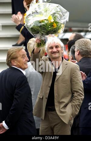 (Dpa) - Fußball-Team Team Chef Rudi Voeller (R) Wellen mit einem Bouquet von Blumen an die deutschen Fans neben Deutsch Soccer Association Präsident Gerhard Mayer-Vorfelder als das Team kommt am Flughafen Frankfurt/Main, 1. Juli 2002. Deutschland gewann die zweite Platzierung bei der WM nach der Niederlage in Stockfoto