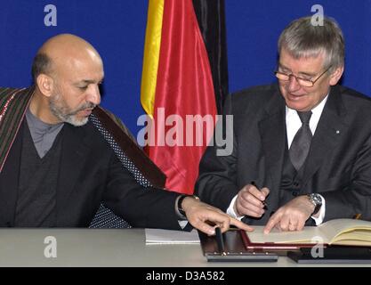 (Dpa-Dateien) - Hamid Karzai (L), Chef der afghanischen Übergangsregierung, Bundesinnenminister Otto Schily zeigt, wo Sie den Vertrag in Berlin 15. März 2002 zu unterzeichnen. Die beiden Länder haben ein Vertrag unterzeichnet, der auf die Hilfe der deutschen Polizei Offiziere der afghanischen Polizei zu rekonstruieren ist damit einverstanden. Karzai Stockfoto