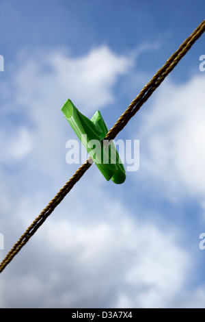 Einem einzigen grünen Wäscheklammer oder Pin an einer Wäscheleine vor einem bewölkten blauen Himmel. Stockfoto