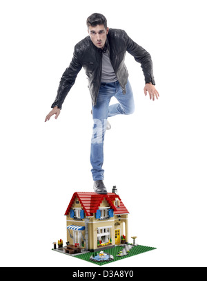 Mann auf einem kleinen Modell eines Hauses ausgeglichen Stockfoto