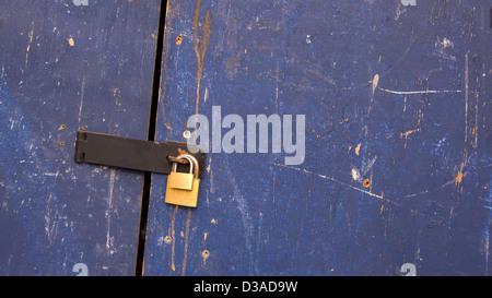 Doppelte Vorhängeschloss auf misshandelte blaue Tür Stockfoto