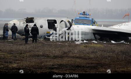 Einsatzkräfte stehen neben eines abgestürzten Flugzeugs auf dem Flughafen in Donezk, Ukraine, 14. Februar 2013. Mindestens fünf Menschen wurden nach einer An-24 Flugzeug Bruchlandung in der Nähe des Flughafens von der Ost-ukrainischen Stadt Donezk, tot wie Beamte sagten. Foto: Marius Becker/dpa Stockfoto