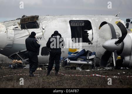 Einsatzkräfte stehen neben eines abgestürzten Flugzeugs auf dem Flughafen in Donezk, Ukraine, 14. Februar 2013. Mindestens fünf Menschen wurden nach einer An-24 Flugzeug Bruchlandung in der Nähe des Flughafens von der Ost-ukrainischen Stadt Donezk, tot wie Beamte sagten. Foto: Marius Becker/dpa Stockfoto